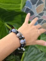 Set di bracciali in pietra agata striata e agata botswana con inserti in argento, indossati al polso su sfondo naturale verde - Collezione Namamālā.