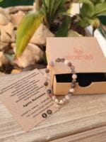 Bracciale con pietre naturali di agata botswana con ciondolo sankofa e posizionato sopra la sua confezione regalo in cartone ecologico con il logo Namamala e foglietto informativo.