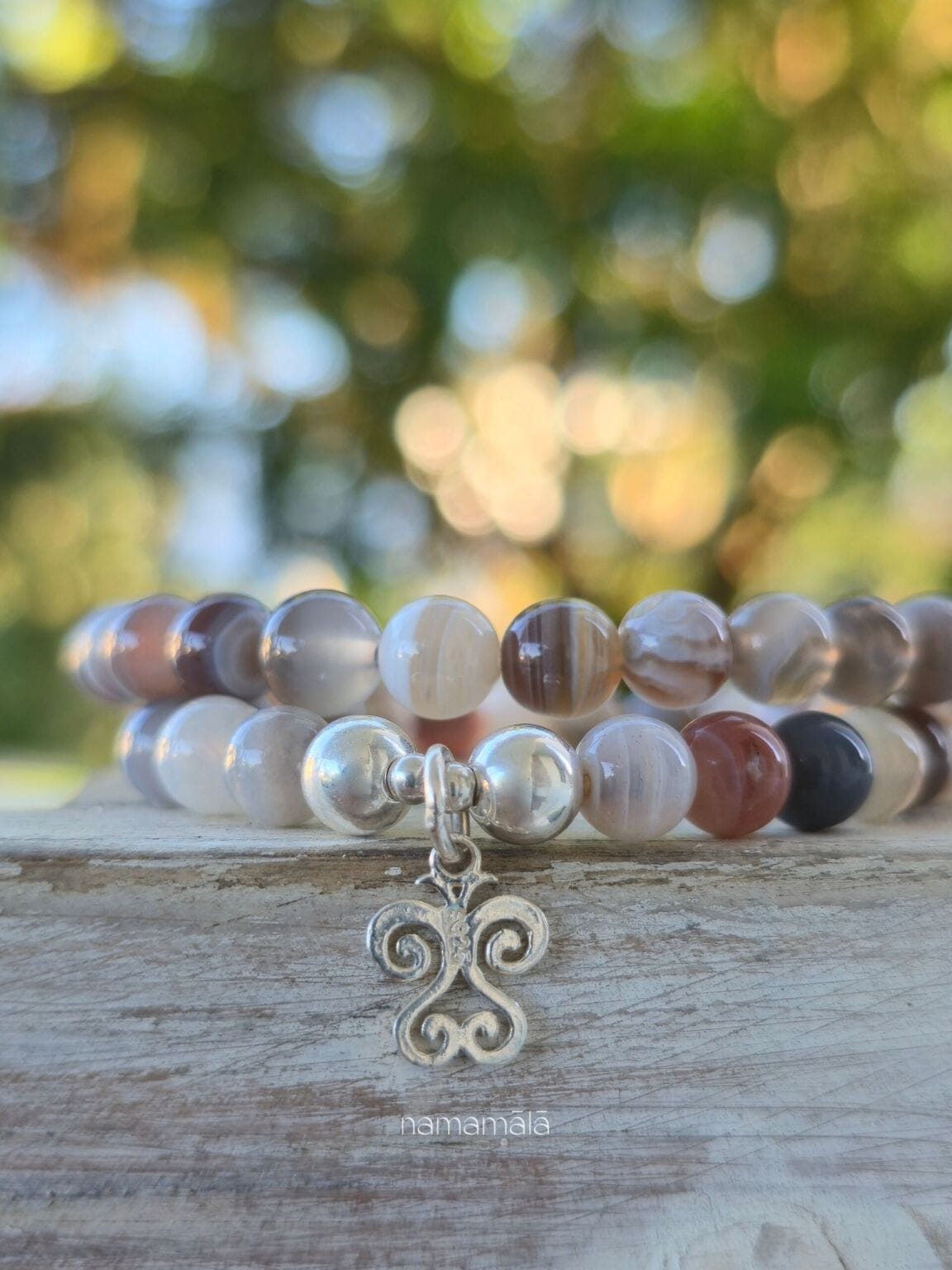 Dettaglio del ciondolo sankofa e delle pietre del bracciale in agata botswana.