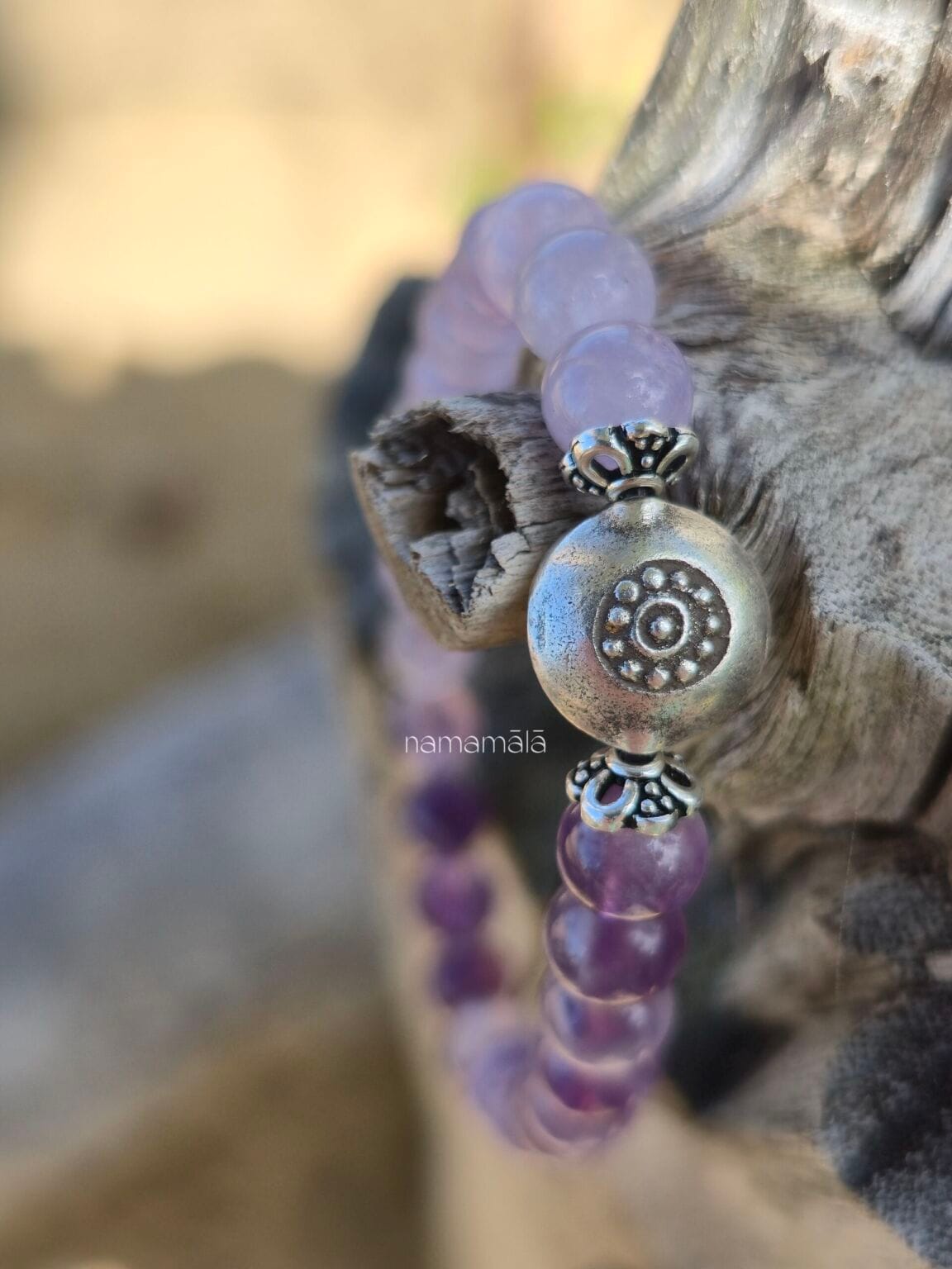 Dettaglio ravvicinato del bracciale Ajna, in ametista, con elemento centrale perla in argento Karen Tribe 97-99%. con uno sfondo naturale di legno.