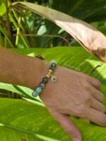 bracciale amazzonite agata muschiata indossato al polso di donna con sfondo una foglia di palma
