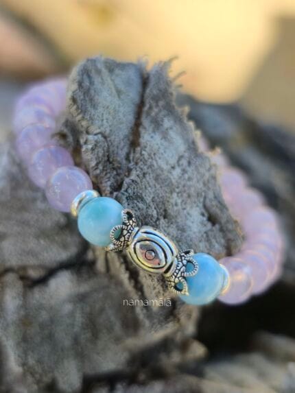bracciale di ametista e larimar con perla centrale in argento 925, appoggiato su un pezzo di legno marino.