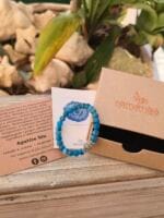 Bracciale in Apatite blu visibile con la sua confezione regalo in cartone ecologico con il logo Namamala e foglietto informativo.