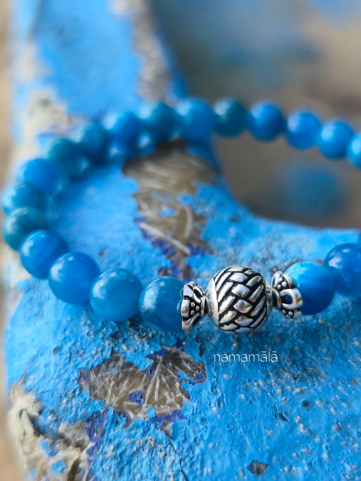 Dettaglio ravvicinato del bracciale in pietre naturali di Apatite blu con elemento centrale perla in argento 925 tribale, su uno sfondo in legno azzurro.