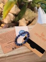 Bracciale in pietre naturali di Cianite blu accanto con la sua confezione regalo in cartone ecologico con il logo Namamala e foglietto informativo.