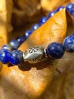 Dettaglio ravvicinato del bracciale "Nel Blu Dipinto di Blu" in pietre naturali di Lapislazzuli con elemento centrale perla a barile con tre facce ed inciso motivo un motivo a croce, in argento Karen Tribe 97-99%.