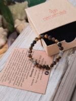 Bracciale con pietre naturali di Occhio di Tigre vicino la sua confezione regalo in cartone ecologico con il logo Namamala e foglietto informativo.