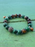 bracciale malachite occhio di tigre appoggiato su un tavolo in legno verde