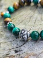 primo piano di pietre dure sferiche di malachite e occhio di tigre con perla centrale in argento 925 lavorata in India