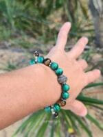 dettaglio di un polso di donna con un bracciale di malachite striata verde e occhio di tigre cangiante