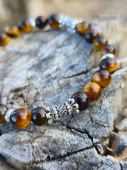 Dettaglio ravvicinato della perla lavorata in argento 925 del bracciale occhio di tigre su sfondo legnoso.