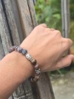 Bracciale da donna e da uomo con pietre naturali di Pietersite dalle sfumature blu e ocra e con elemento centrale in argento lavorato Karen Tribe indossato al polso.