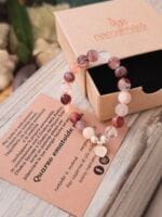 Bracciale con pietre naturali di quarzo ematoide e ciondolo con incisione doppio dorje (vajra) e posizionato sopra la sua confezione regalo in cartone ecologico con il logo Namamala e foglietto informativo.