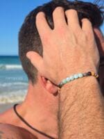 bracciale uomo indossato in spiaggia con pietre di larimar e quarzo fumè e semi di rudraksha namamala