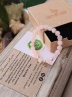 Bracciale con pietre naturali di Quarzo rosa e appoggiato sopra alla sua confezione regalo in cartone ecologico con il logo Namamala e foglietto informativo.