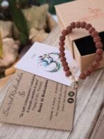 Bracciale con sacri semi indiani di rudraksha vicino la sua confezione regalo in cartone ecologico con il logo Namamala e foglietto informativo.