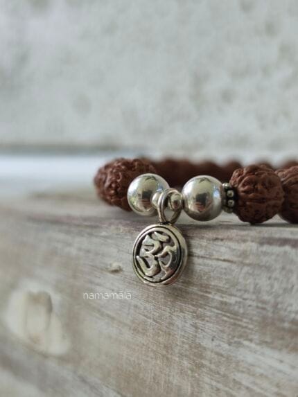 dettaglio del simbolo sacro om presente nel bracciale sacred rudraksha in semi indiani