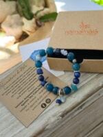Bracciale con pietre naturali di Apatite blu, Lapislazzuli, Cianite blu, Larimar, Calcedonio blu, acquamarina appoggiato alla sua confezione regalo in cartone ecologico con il logo Namamala e foglietto informativo.