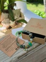 Bracciale con pietre naturali di Turchese africano, Crisoprasio, Giada verde Birmania, Prehnite, Florite verde appoggiato alla sua confezione regalo in cartone ecologico con il logo Namamala e foglietto informativo.