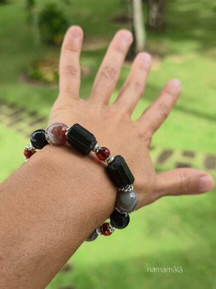 bracciale in tormalina nera sia a sfere che grezza, agata del botswana e perle di ambra, indossato al polso con dettagli in argento.