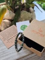Bracciale con pietre naturali di turchese africano appoggiato sopra la sua confezione regalo in cartone ecologico con il logo Namamala e foglietto informativo.