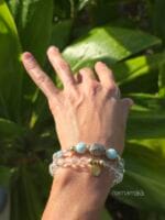 Bracciali da donna con pietre naturali di Quarzo ialino e distanziatori in argento 925, indossati al polso con un contesto di natura e foglie verdi illuminate dal sole.